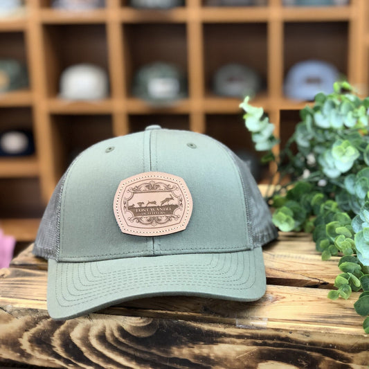 Green cap with a leather patch on a wooden surface with plants in the background
